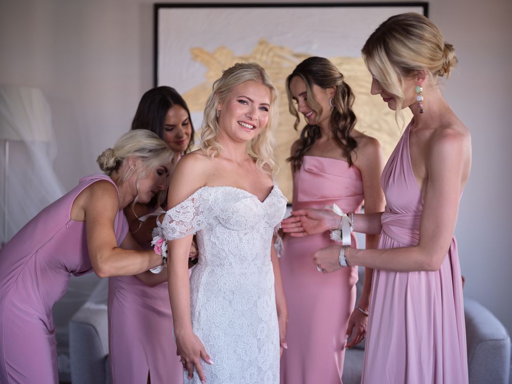 Wedding party in pink dresses helps with final bridal preparations indoors. Photoshoot by Venice Photographer Alina Indi