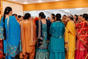 Group of people at an Indian celebration wearing colorful traditional outfits in blue, orange, yellow and red saris and suits.
