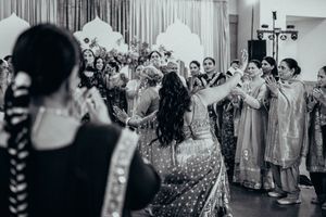 Black and white photo of wedding guests dancing and celebrating during a lively dance party at a reception.