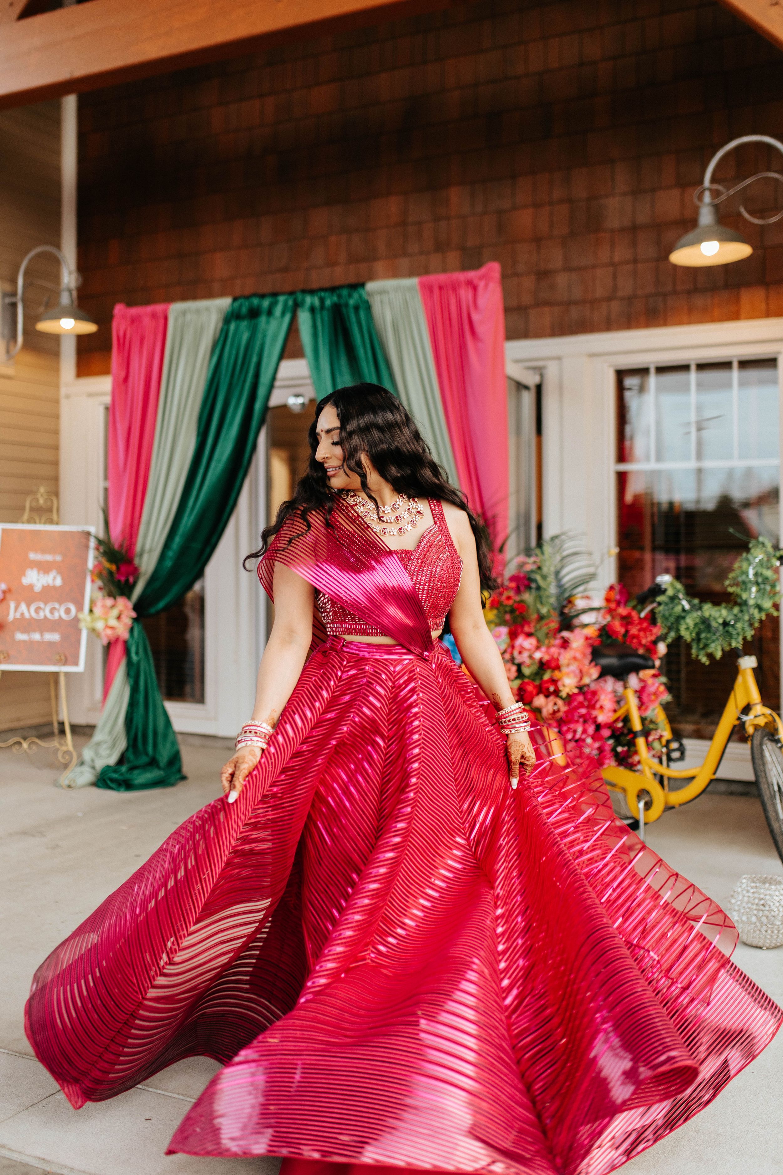 A flowing fuchsia ball gown with textured stripes twirls elegantly in front of emerald and pink curtains.