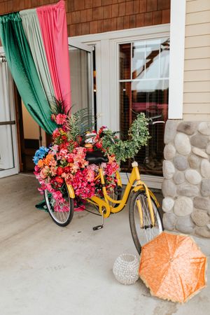 Vibrant pink and teal curtains frame a doorway decorated with colorful flowers and a yellow bicycle prop.
