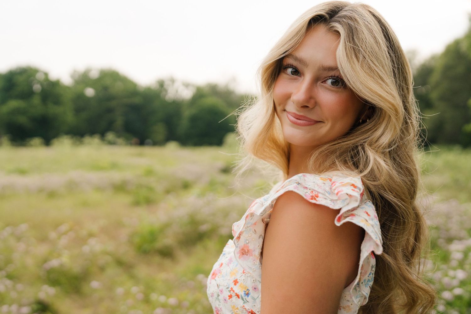 A floral two-piece outfit with a crop top and maxi skirt styled in a dreamy meadow with white wildflowers.