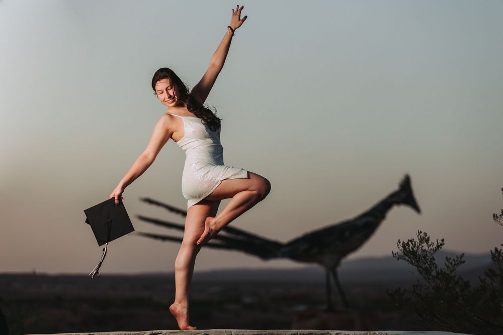 Ballet dancer performs graceful leaps and poses outdoors against a misty mountain landscape at sunset.