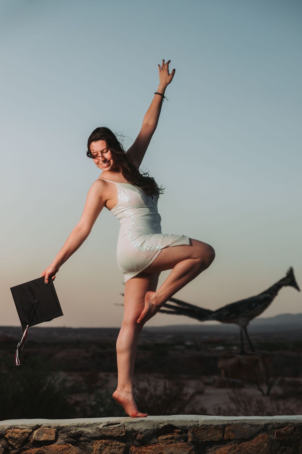 Dancer performs graceful leaping poses atop stone wall against sunset sky in artistic photo sequence.