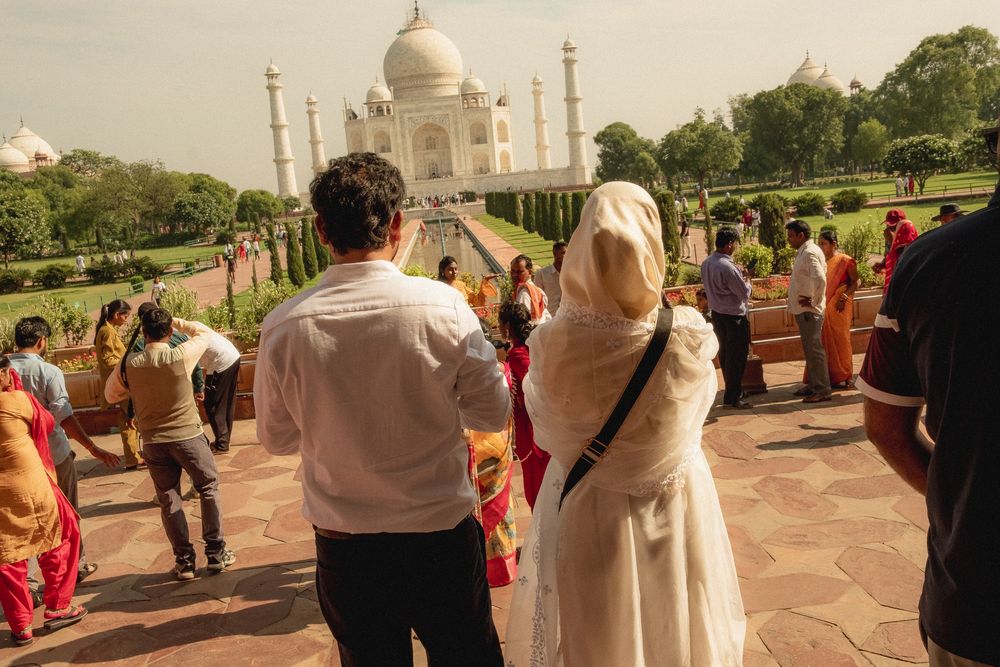 Tourists admiring the iconic Taj Mahal from a distance on a sunny day.