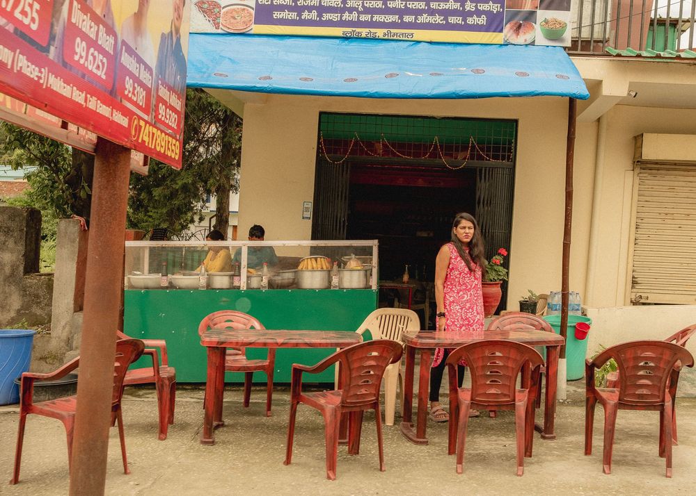 A small restaurant with red plastic chairs and colorful signage in India.