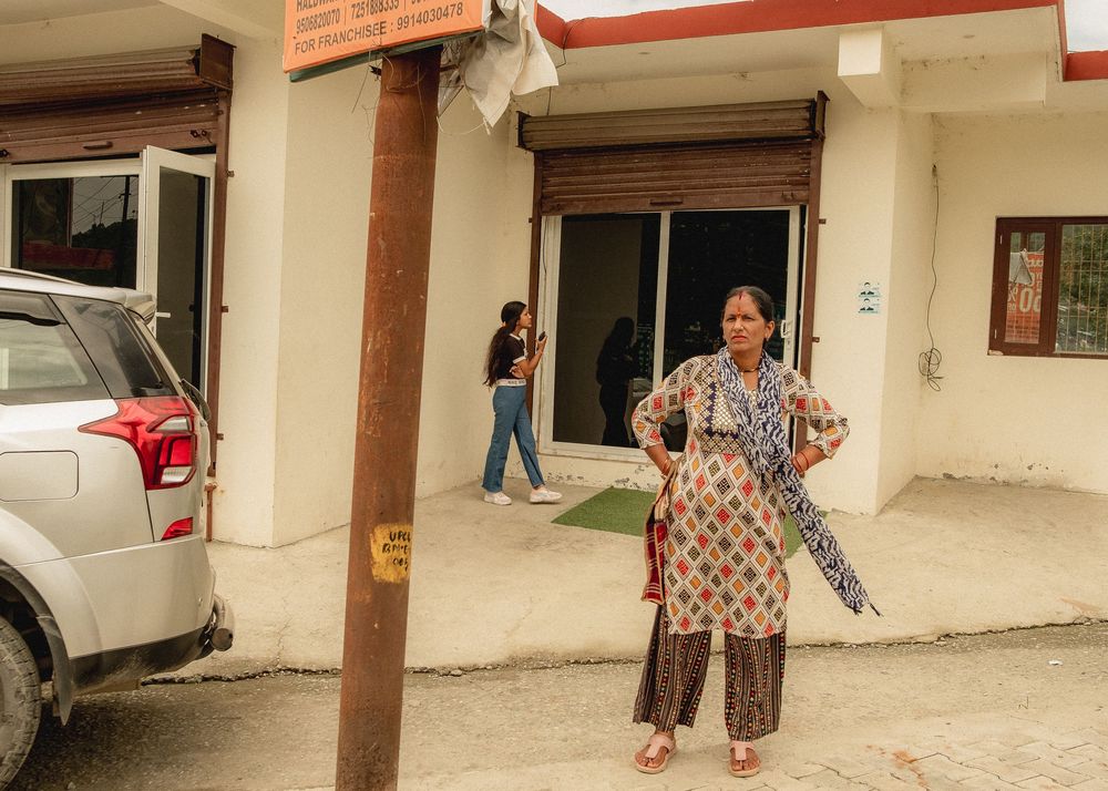 People standing outside a white building with parked cars in an urban area.