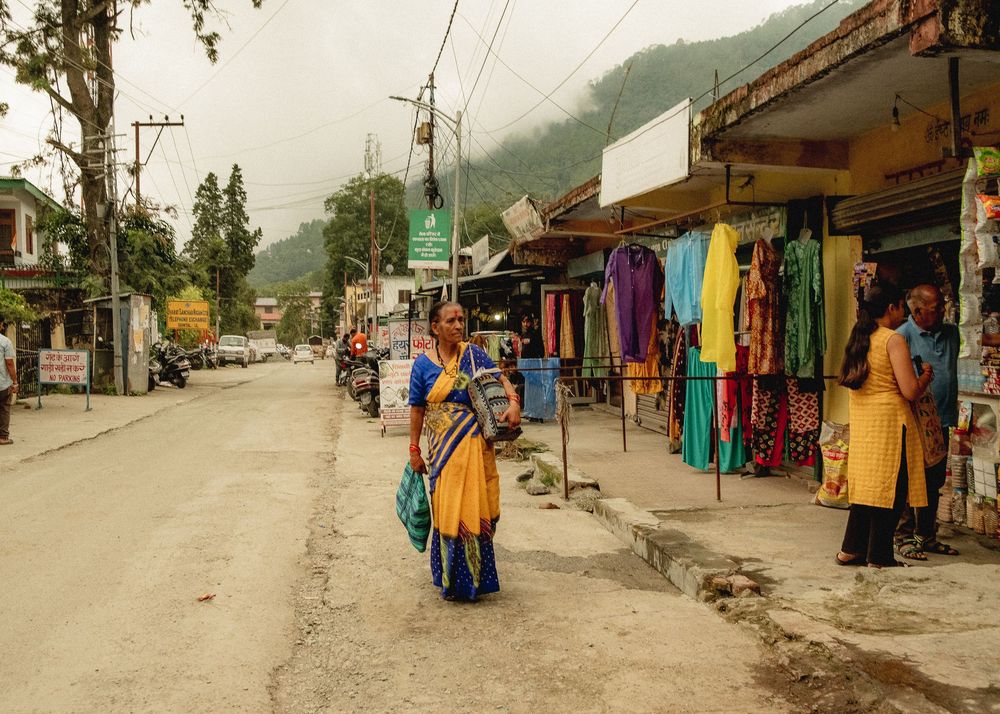 Mountain village street with shops and colorful clothing displays.