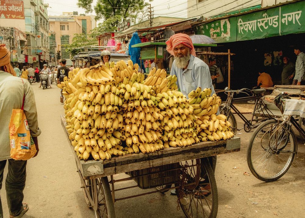 A street vendor's cart loaded with fresh yellow bananas in what appears to be an Asian market setting.