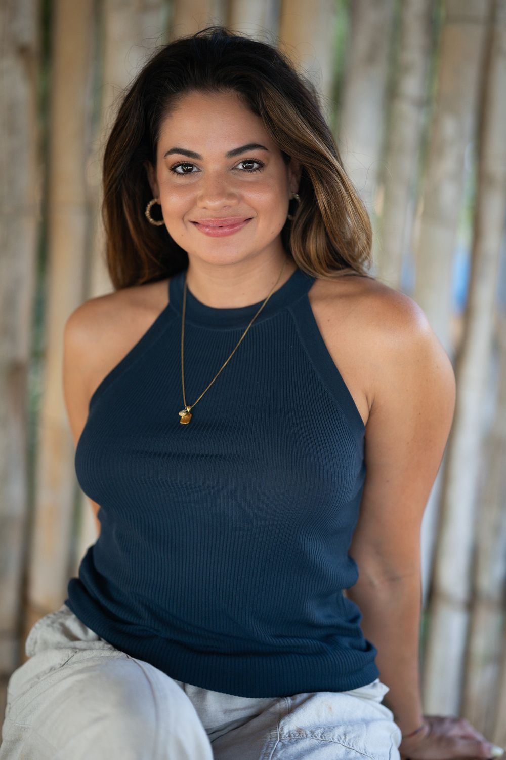 Woman wearing a navy sleeveless top smiles warmly while posing in a series of natural outdoor portraits.