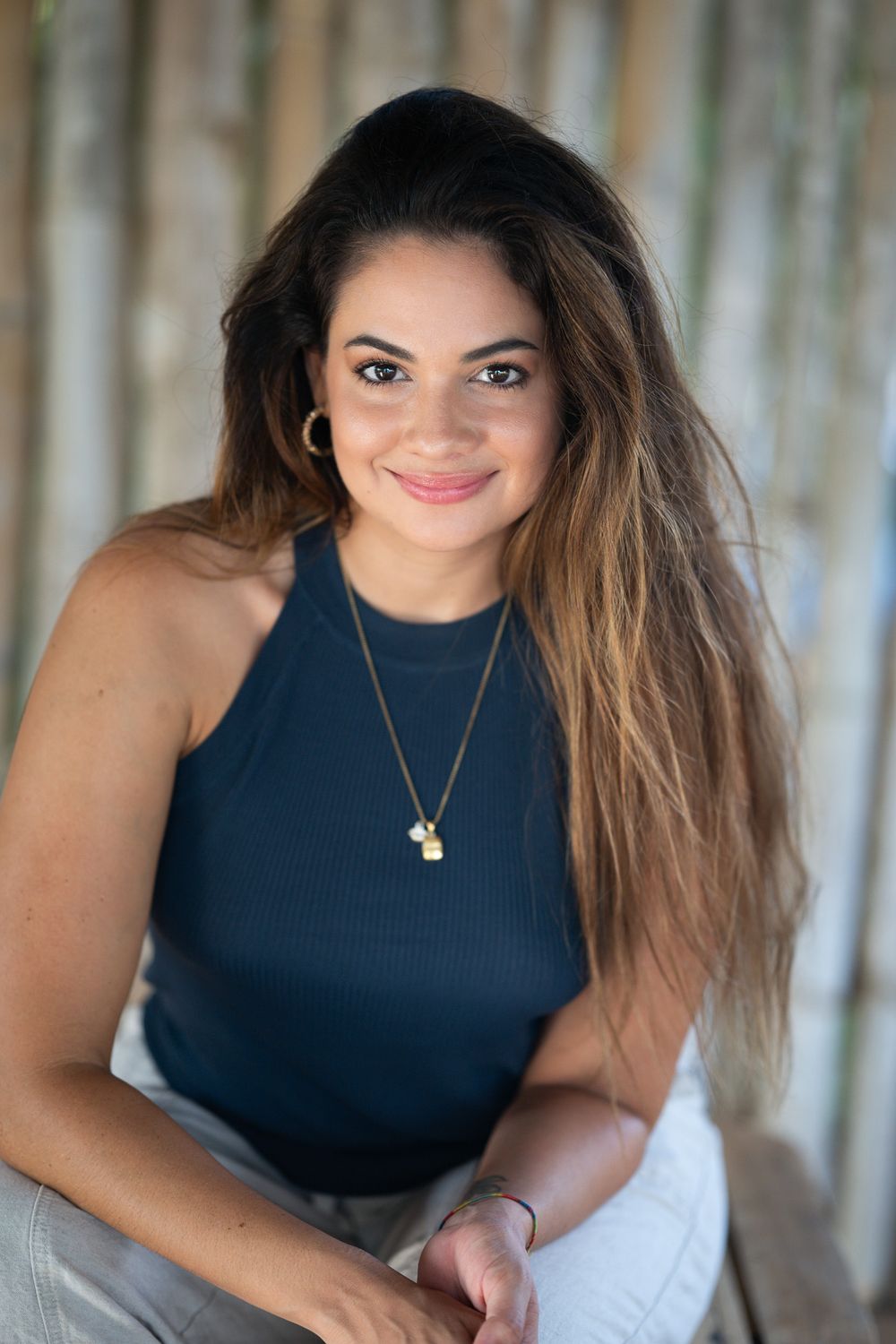 A series of portrait-style photos showing someone posing outdoors in a sleeveless navy top and delicate necklace.