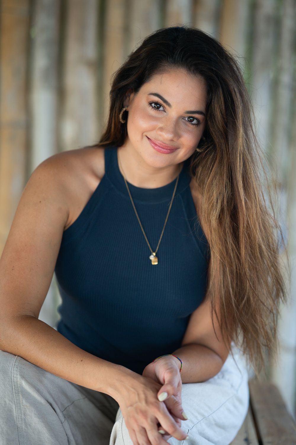 Fashion photo series showing a person in a navy sleeveless top with long wavy hair posing against a textured backdrop.
