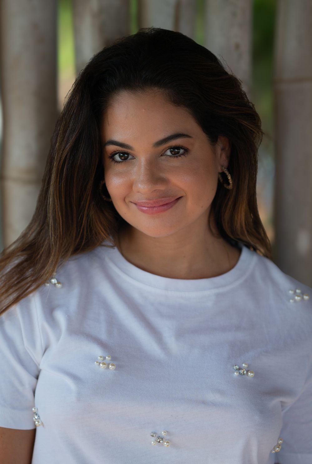 Close-up portrait in white embellished t-shirt with natural bamboo backdrop.