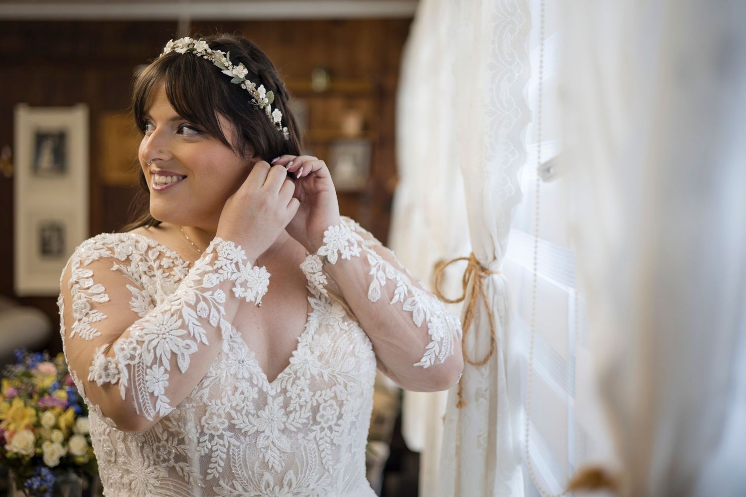 A bride in a delicate lace wedding dress with long sleeves is getting ready for her special day.