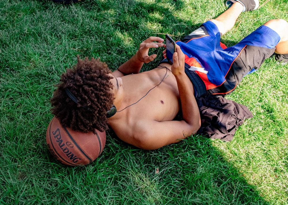 A shirtless person lying on grass with a basketball.