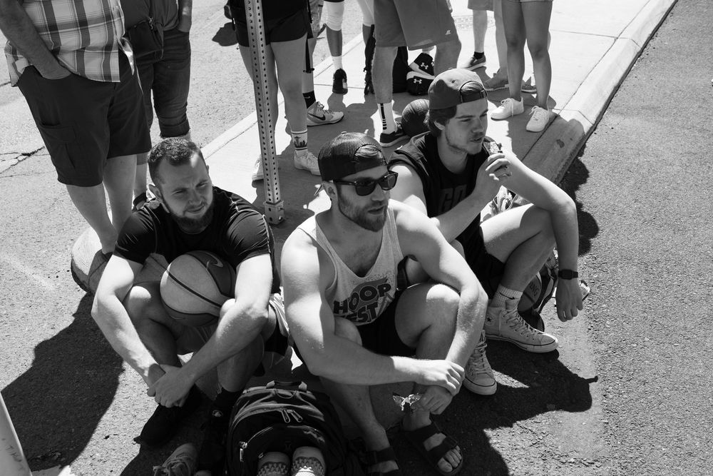 Group of people sitting on the ground at an outdoor event wearing casual clothing.