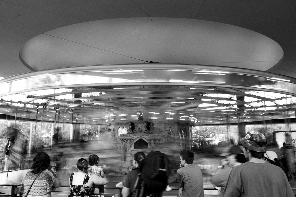 Blurred motion black and white photo of busy dining area with circular ceiling lights.