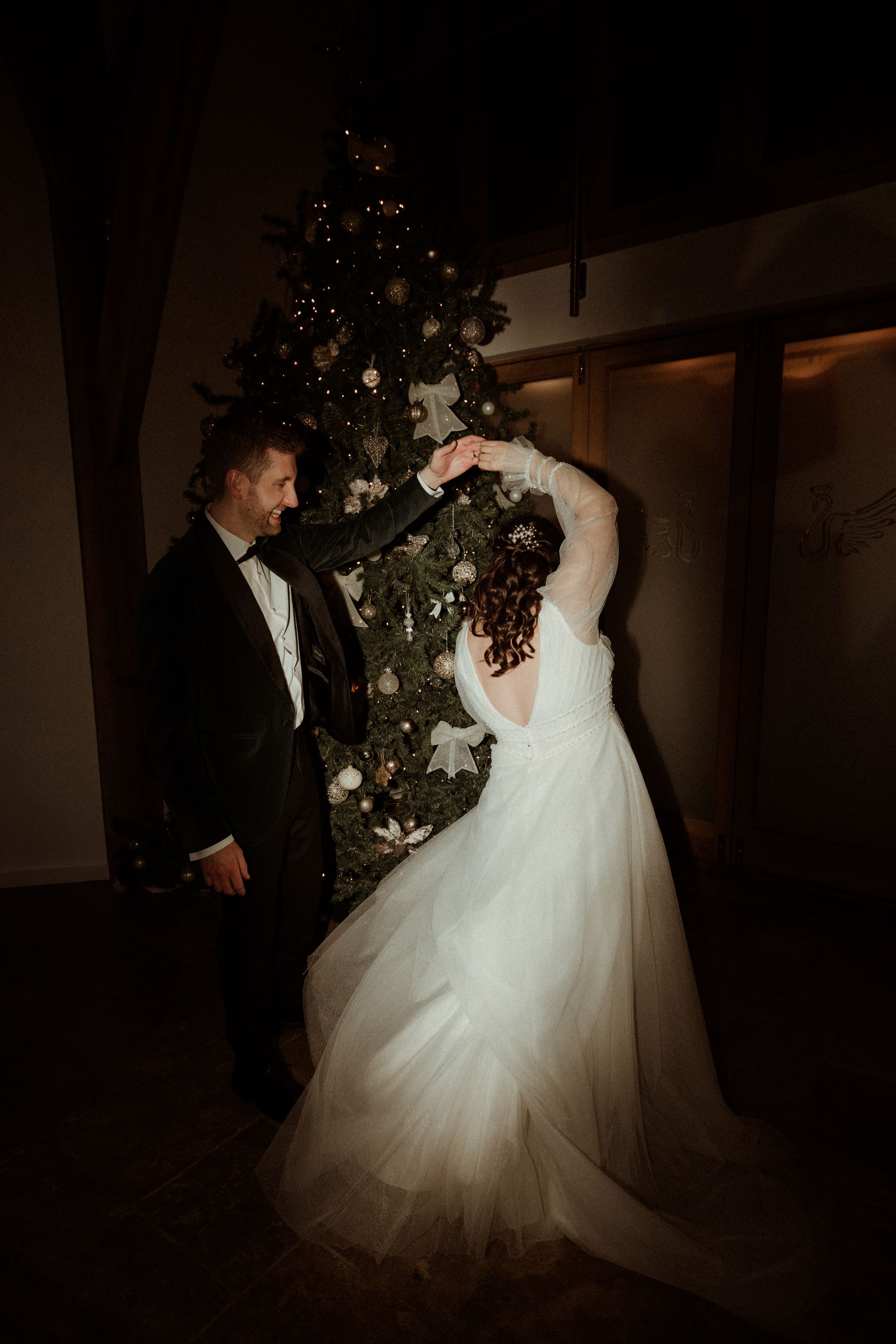 Couple slow dances in dimly lit ballroom with white wedding dress and elegant decor.