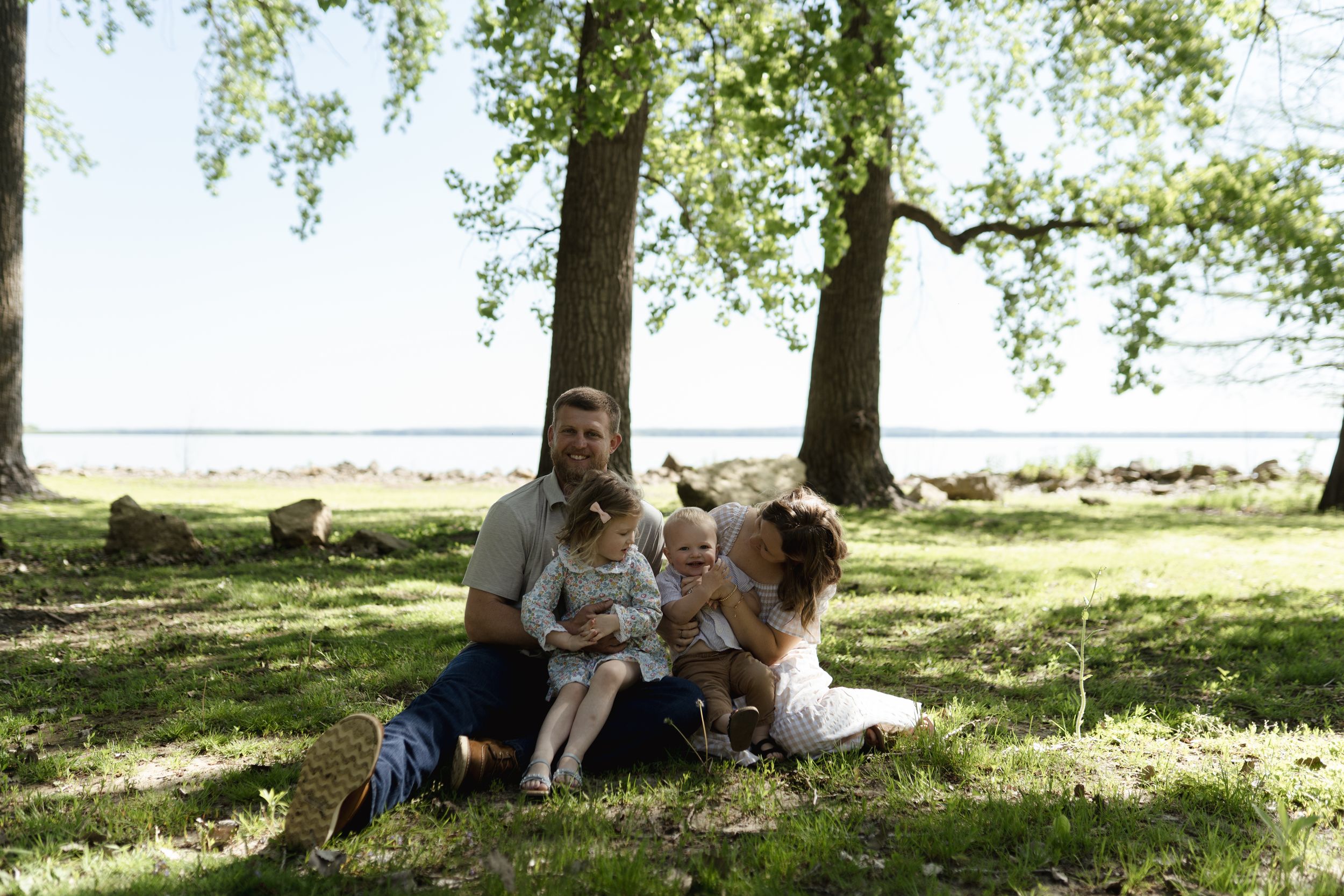 Family relaxing under shady trees on sunny afternoon.