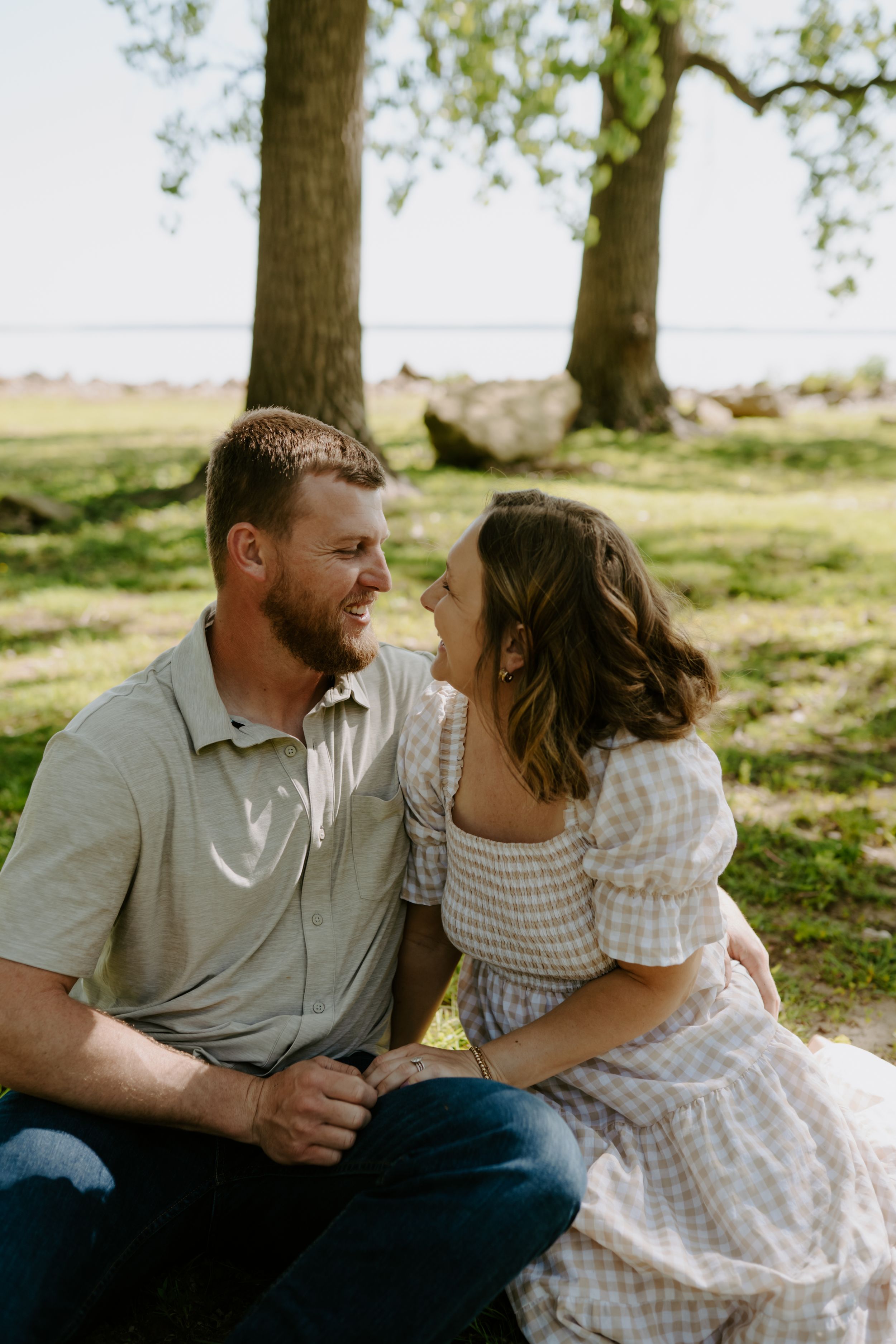 Intimate couple moment captured under shady trees during an outdoor photoshoot.