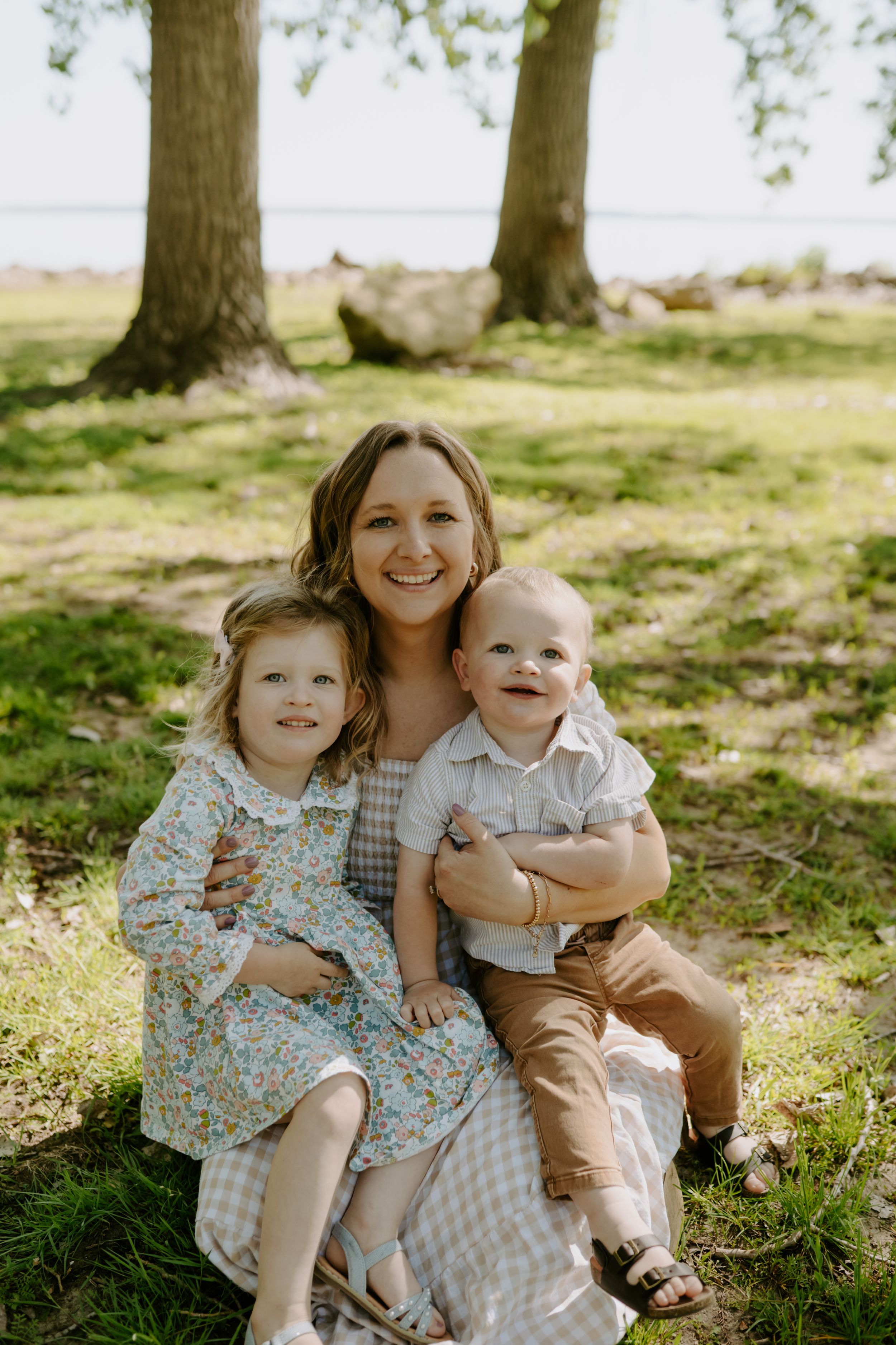 Sweet outdoor family moment captured under trees on a bright spring day.