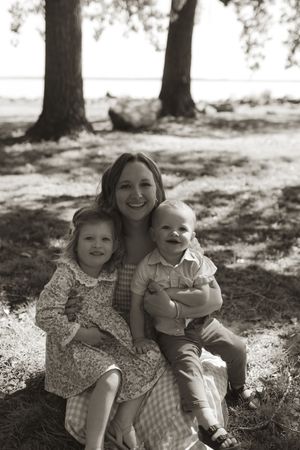 Black and white family portrait showing tender moments under tree shade.