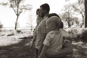 Black and white portrait of a family sharing an intimate moment in a natural outdoor setting.