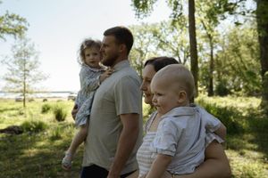 Candid family photoshoot in a sunlit wooded area during golden hour.