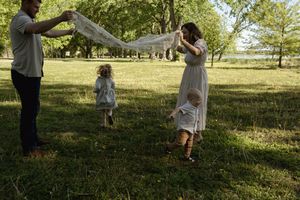 Family creating a canopy with white fabric in a peaceful park setting.
