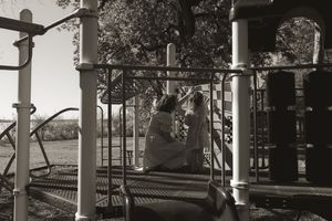 Black and white photo of children playing on playground equipment.