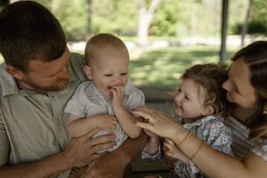 A tender family moment captured on a wooden bench in dappled sunlight.
