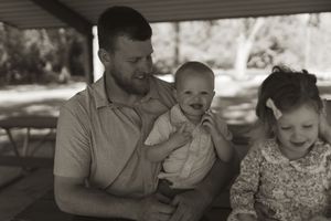 A joyful family moment shared on a shaded park bench during a sunny day.