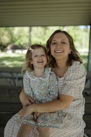 A cheerful family moment filled with laughter on a wooden bench in a park setting.