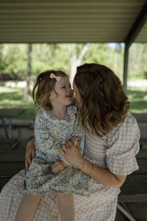An affectionate family scene unfolds on a shaded bench in a peaceful park setting.