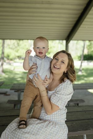 A joyful outdoor photoshoot showing playful moments between a parent and baby under a covered shelter.