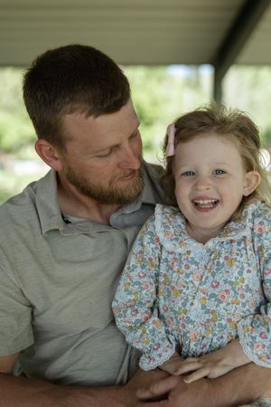 Sweet candid moments captured between parent and child sitting together under a covered outdoor area.