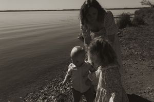 A black and white photo captures a family's silhouette against a waterfront landscape.