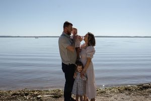 A loving family moment captured against a serene lake backdrop.