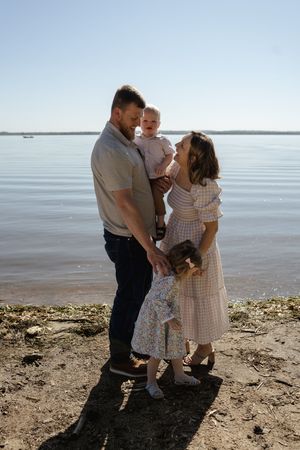 A tender family moment shared on a beach with sparkling water in the distance.