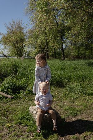 A child sits on a log in a grassy area on a sunny spring day.