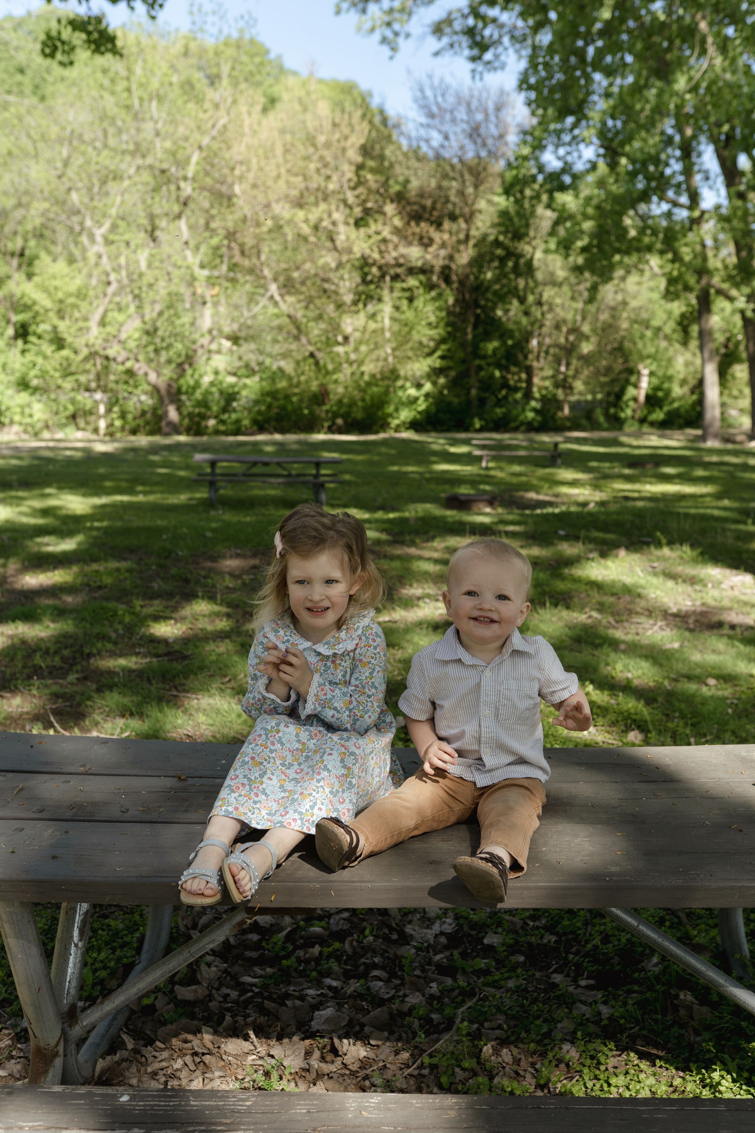Two small children sharing a moment of joy while sitting on a park bench.