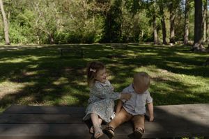 Children playing and laughing while sitting on a wooden bench in a park setting.