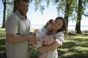 Joyful family embracing and laughing together outdoors on a sunny day.