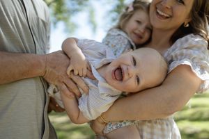 Happy family playing and laughing together during an outdoor photoshoot.