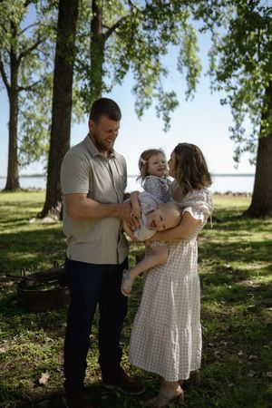 Intimate family photos taken in a scenic park with trees and natural lighting.
