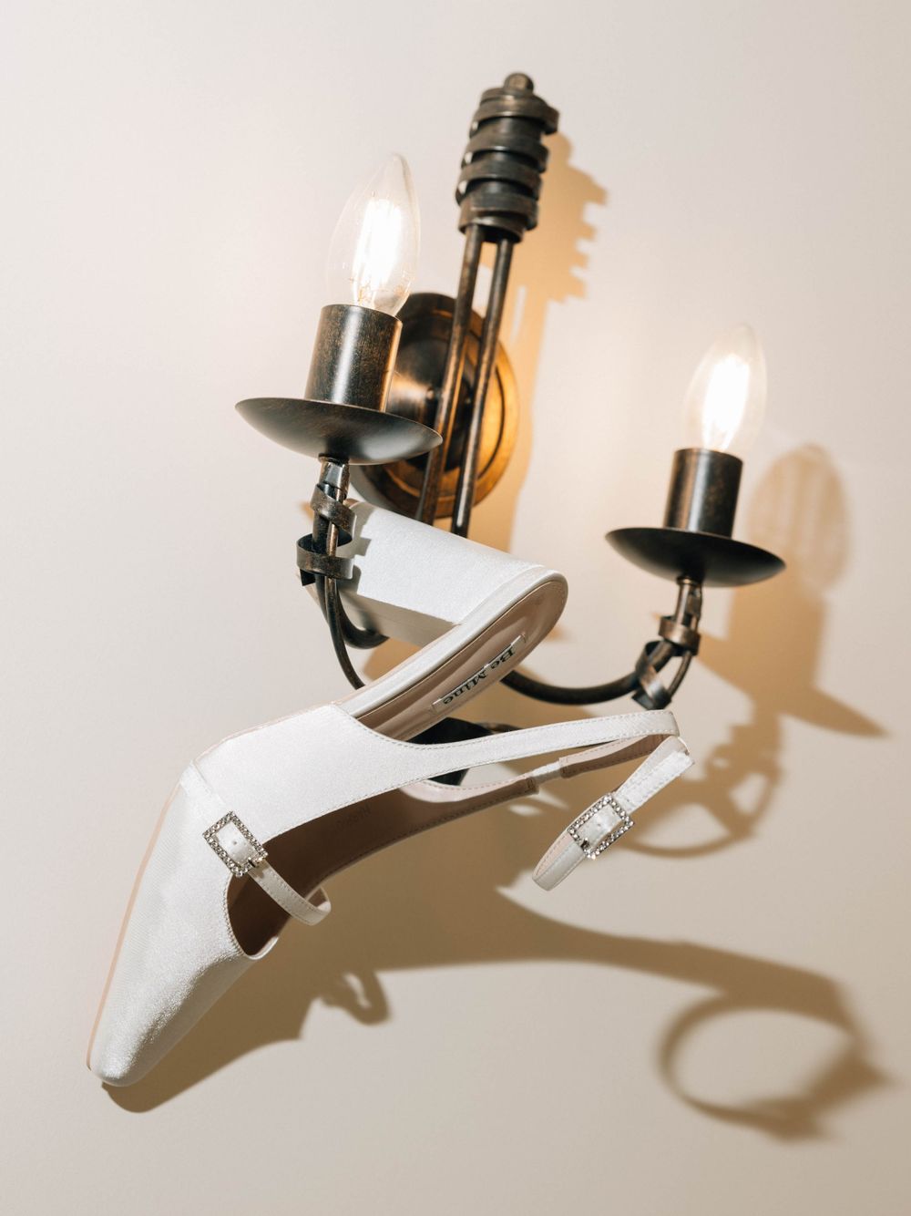 An elegant wall-mounted candle sconce with white decorative elements casting dramatic shadows.