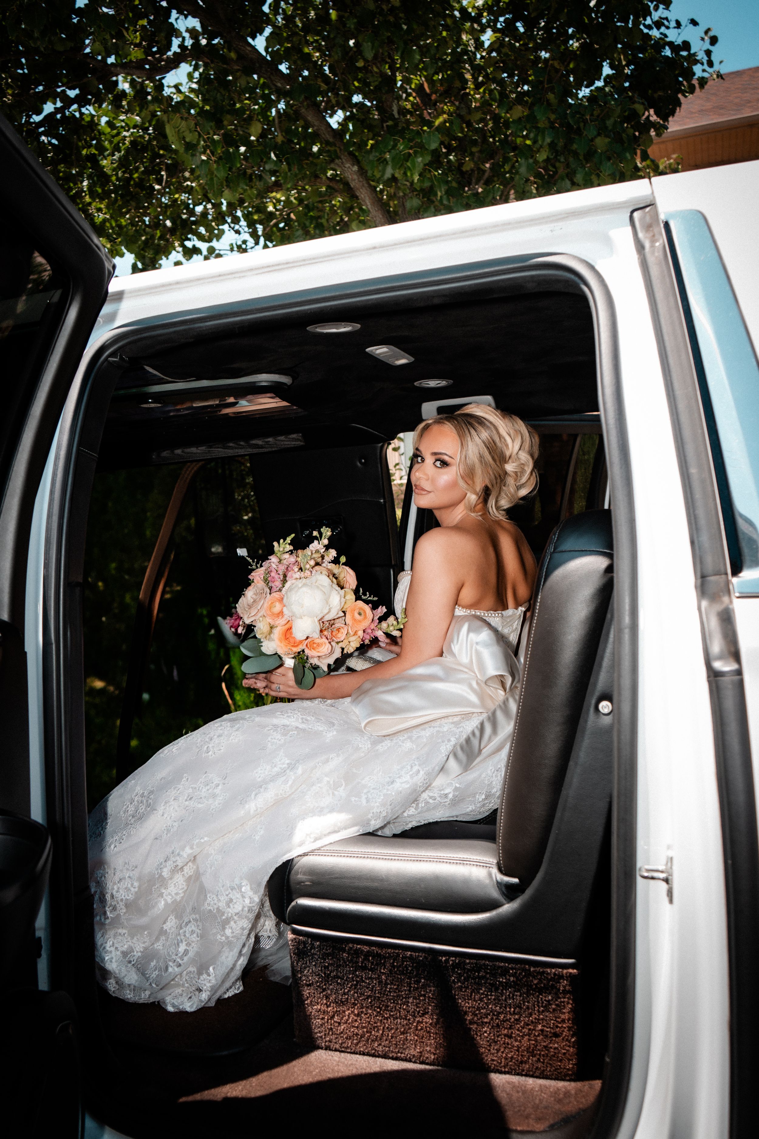 A silhouetted wedding dress hangs in front of an arched window with dramatic backlighting casting elegant shadows.