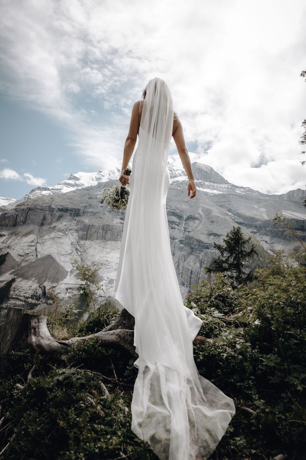 A flowing white wedding dress swaying in the wind against a dramatic mountain backdrop.