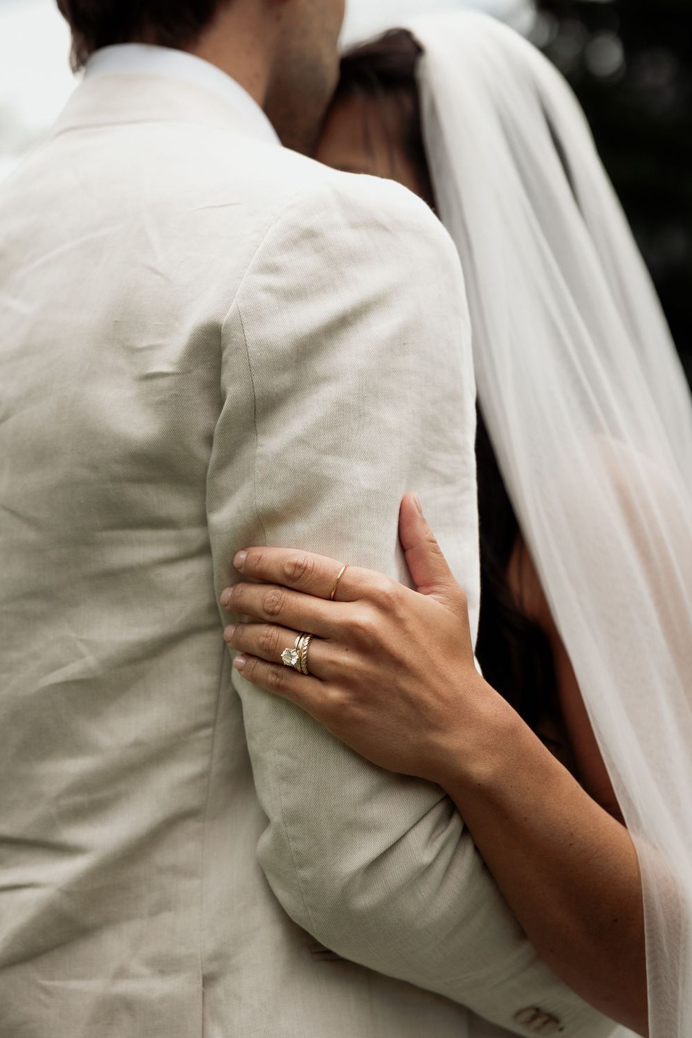 Close-up shot of hands touching white fabric, with an engagement ring visible.