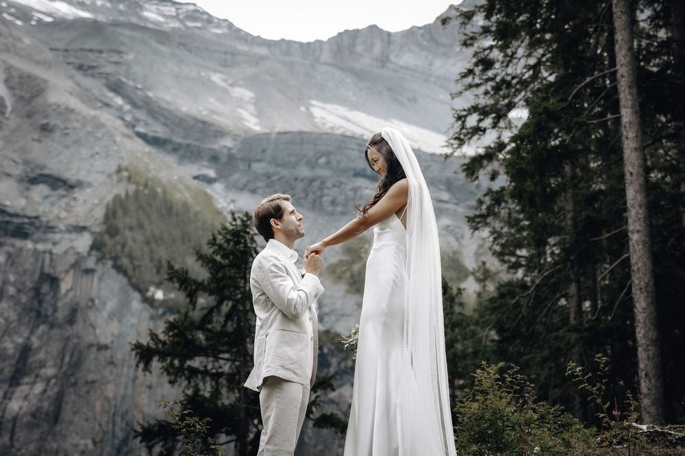 A couple shares a romantic moment against a backdrop of majestic mountain scenery.
